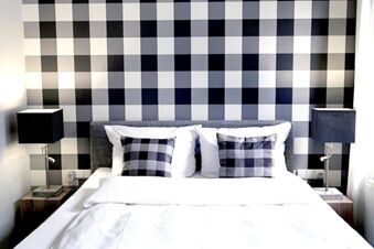 Alt N&uuml;rnberg Hotel 的臥室裝潢現代化，背景為棋盤格紋，配有靠墊和燈具，為您提供舒適的住宿環境。
