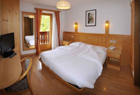 &Uacute;tuln&yacute; hotelov&yacute; pokoj s manželskou postel&iacute;, dřevěn&yacute;m n&aacute;bytkem a balkonem s v&yacute;hledem v hotelu Albergo Nido Verde, ide&aacute;ln&iacute; pro relaxačn&iacute; noci.