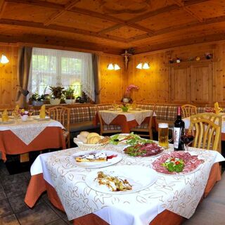 &Uacute;tuln&aacute; restaurace v hotelu Albergo Nido Verde s dřevěn&yacute;mi stěnami, prostřen&yacute;mi stoly a různ&yacute;mi pokrmy na jednom stole.