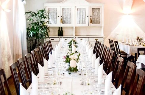 Long dining table with white napkins, glassware, candles, and flowers in a restaurant at Brauereigasthof und Hotel Kapplerbr&auml;u