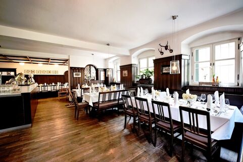 Dining area with wooden floors, tables set with white linens and glassware inside Brauereigasthof und Hotel Kapplerbr&auml;u