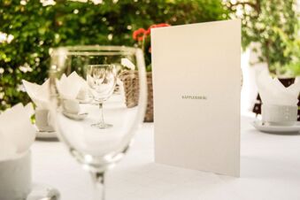 White menu card with Kapplerbr&auml;u text on a table set with wine glasses and napkins at Brauereigasthof und Hotel Kapplerbr&auml;u