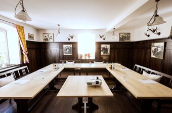Meeting room with U-shaped wooden tables, chairs, drinking glasses, a projector, and wall decorations at Brauereigasthof und Hotel Kapplerbr&auml;u