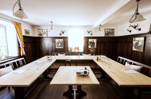 Meeting room with U-shaped wooden tables, chairs, drinking glasses, a projector, and wall decorations at Brauereigasthof und Hotel Kapplerbr&auml;u