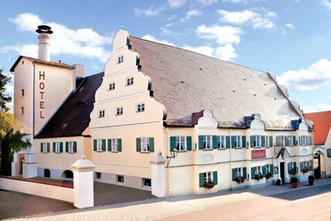 Large cream-colored building with green window shutters and a steep brown tiled roof of Brauereigasthof und Hotel Kapplerbr&auml;u
