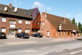 Ansicht der Fassade von Hotel garni Zur Krim mit mehreren Geb&auml;uden, parkenden Autos und klarem Himmel im Hintergrund.