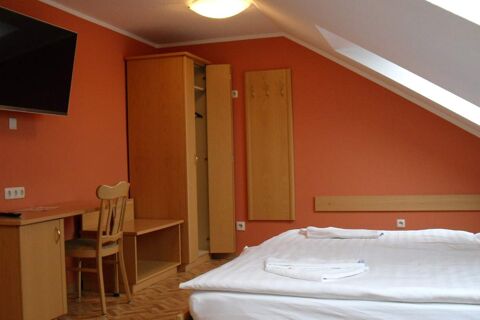 Accogliente camera dell'Hotel garni Zur Krim con soffitto spiovente, due letti, armadio e scrivania dai colori caldi.