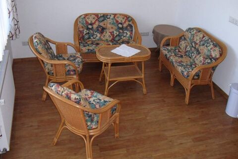 Rattan furniture set with patterned cushions and a small table with a white cloth in a room at Hotel garni Zur Krim