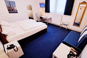 Hotel Columbus & Glamping room with two single beds, navy blue carpet, small desk with chair, wall mirror, and a blue and white couch