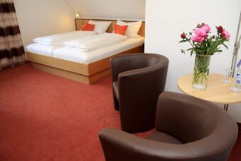 Hotel room at Rh&ouml;ngasthof Zur Linde & Ferien-Appartements Rh&ouml;nsicht with two single beds, brown chairs, and a flower vase on a round wooden table