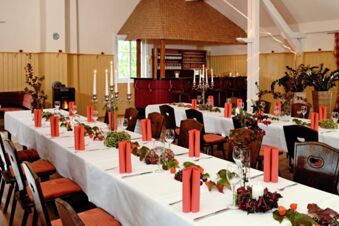 Banquet tables with white tablecloths and orange napkins arranged with wine glasses and candles at Rh&ouml;ngasthof Zur Linde & Ferien-Appartements Rh&ouml;nsicht
