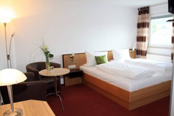 Hotel room at Rh&ouml;ngasthof Zur Linde & Ferien-Appartements Rh&ouml;nsicht with two single beds, a small table, two chairs, and a window with curtains