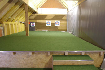 Archery range indoors with three paper targets mounted on a wooden wall at Rh&ouml;ngasthof Zur Linde & Ferien-Appartements Rh&ouml;nsicht