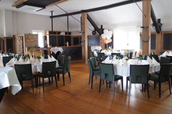Dining area with round tables set with white tablecloths and green chairs inside Rh&ouml;ngasthof Zur Linde & Ferien-Appartements Rh&ouml;nsicht