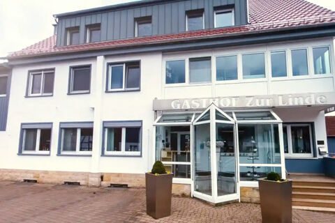 Front entrance of Rh&ouml;ngasthof Zur Linde & Ferien-Appartements Rh&ouml;nsicht with glass doors, windows, and two tall planters