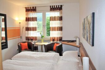 Hotel room at Rh&ouml;ngasthof Zur Linde & Ferien-Appartements Rh&ouml;nsicht with double bed, two chairs, table, and window with striped curtains