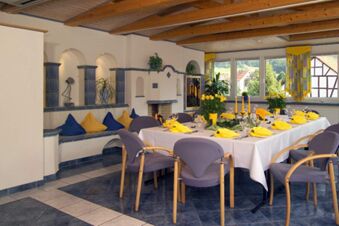 Dining room with a white tablecloth, yellow napkins, candles, plants, and eclectic seating at Rh&ouml;ngasthof Zur Linde & Ferien-Appartements Rh&ouml;nsicht