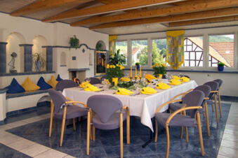 Dining area with a table set with yellow napkins, glassware and flowers at Rh&ouml;ngasthof Zur Linde & Ferien-Appartements Rh&ouml;nsicht