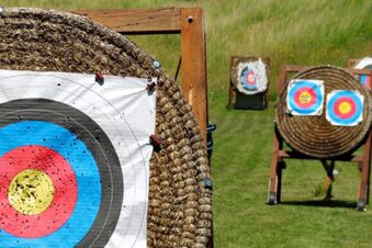 Three archery targets with multicolored paper faces on straw mats on wooden stands on grass at Rh&ouml;ngasthof Zur Linde & Ferien-Appartements Rh&ouml;nsicht