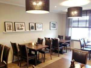 Gem&uuml;tlicher Essbereich mit dunklen Holztischen, St&uuml;hlen und gedimmtem Licht im Restaurant von K&ouml;hncke's Hotel.
