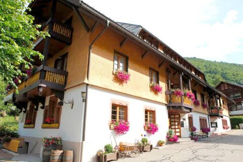 Hotel Gasthaus Hirschen building with wooden balconies, flower pots under windows, barrels, and greenery around the entrance