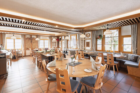 Dining area with wooden tables, chairs, and bench seating under hanging lights at Hotel Gasthaus Hirschen