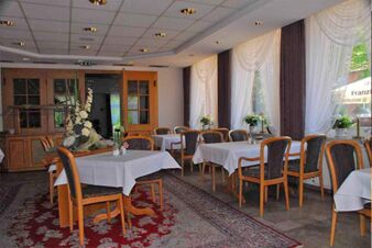 Helles und gepflegtes Restaurant im Landhotel Helms mit gedeckten Tischen, Holzst&uuml;hlen und gro&szlig;en Fenstern mit wei&szlig;en Vorh&auml;ngen.