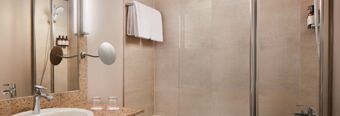 Modernes Badezimmer mit Dusche, Handt&uuml;chern und Waschbecken im NH Collection Hotel Heidelberg, elegant und einladend gestaltet.