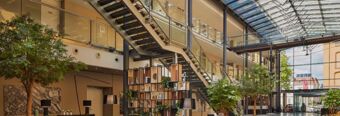 Heller und moderner Lobbybereich mit gro&szlig;er Glasdecke, Pflanzen und offener Treppe im NH Collection Hotel Heidelberg.