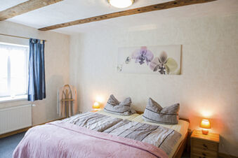 Hell eingerichtetes Schlafzimmer mit zwei Betten, Nachttischlampen und Blumenbild im Ferienhof Klaucke f&uuml;r entspannte N&auml;chte.