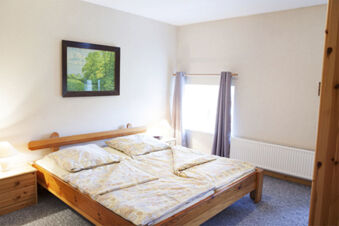 Helles und gem&uuml;tliches Schlafzimmer mit Holzm&ouml;beln und einem Fenster im Ferienhof Klaucke, einfach und einladend eingerichtet.