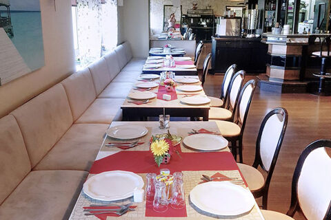 Das elegante Restaurant von Hotel Kick zeigt gedeckte Tische mit wei&szlig;en Tellern, roten Tischl&auml;ufern und bequemen St&uuml;hlen.