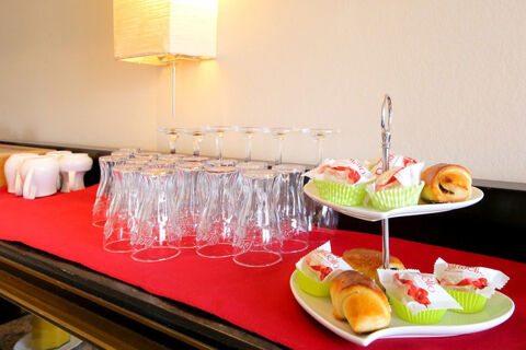 Ein Buffet mit Gl&auml;sern, Kaffetassen und Geb&auml;ck auf einem roten Tuch, arrangiert im Hotel Kick f&uuml;r G&auml;ste.