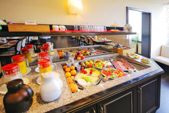 Fr&uuml;hst&uuml;cksbuffet mit frischem Obst, Aufschnitt, K&auml;se und S&auml;ften im hellen Restaurant des Hotel Kick mit gem&uuml;tlichen Sitzgelegenheiten.