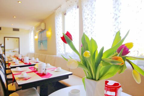 Heller Fr&uuml;hst&uuml;cksraum mit gedeckten Tischen und bunten Tulpen im Vordergrund im Hotel Kick sorgt f&uuml;r angenehme Atmosph&auml;re.
