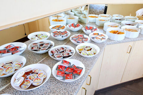 Hotel Kick Fr&uuml;hst&uuml;ckstheke mit verschiedenen Marmeladen, Honigportionen und mehreren Schalen voller Cerealien und Cornflakes.