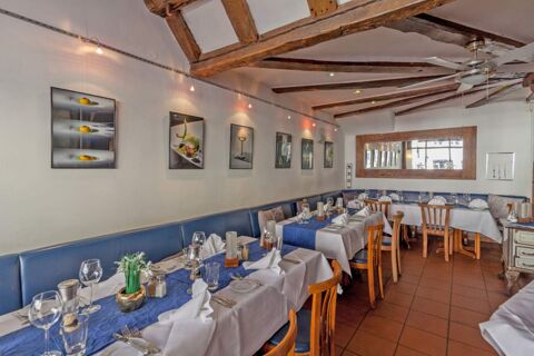 Dining area at Marktplatzhotel u. Bistrorant Tafelspitz with wooden chairs, blue and white tablecloths, and framed artwork on walls
