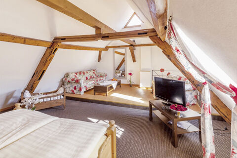 Gem&uuml;tliches G&auml;stezimmer mit sichtbaren Holzbalken, floralen M&ouml;beln und Tageslicht im Marktplatzhotel u. Bistrorant Tafelspitz.