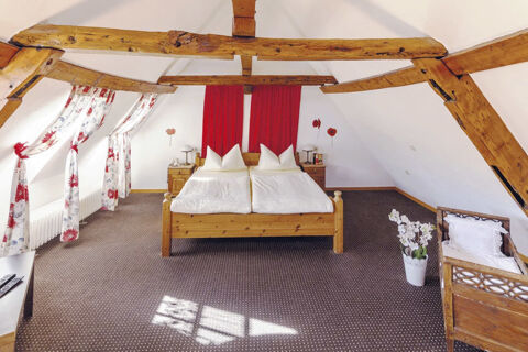 Gem&uuml;tliches Zimmer mit Holzdecke, Doppelbett und rot-blumigen Vorh&auml;ngen im Marktplatzhotel u. Bistrorant Tafelspitz.