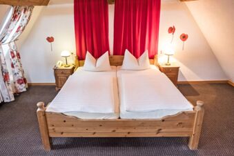 Double wooden bed with white linens and pillows flanked by nightstands with lamps in a room at Marktplatzhotel u. Bistrorant Tafelspitz