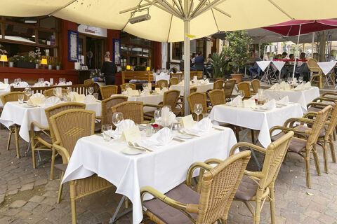Geschmackvoll gedeckte Au&szlig;enterrasse mit wei&szlig;en Tischdecken und Korbst&uuml;hlen im Marktplatzhotel u. Bistrorant Tafelspitz.
