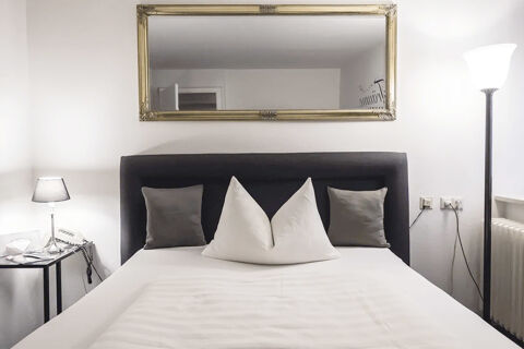 Modern eingerichtetes Hotelzimmer mit Bett, Kissen und Spiegel im Marktplatzhotel u. Bistrorant Tafelspitz.