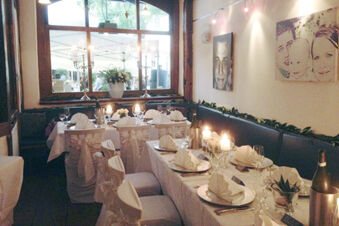 Dining area at Marktplatzhotel u. Bistrorant Tafelspitz with white covered chairs, folded napkins, candles, and table settings