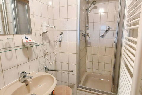 Kleines Badezimmer mit Dusche, Waschbecken, F&ouml;hn und Handtuchheizung im Bauernhof W&auml;ldebauernhof, funktional ausgestattet.