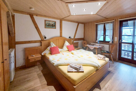 Gem&uuml;tliches G&auml;stezimmer mit Holzm&ouml;beln, Doppelbett und Balkon im Bauernhof W&auml;ldebauernhof mit l&auml;ndlichem Flair.