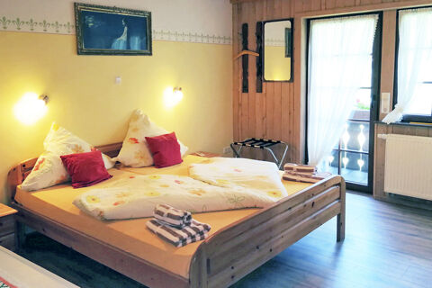 Gem&uuml;tliches Doppelzimmer mit Holzm&ouml;beln, blumiger Bettw&auml;sche und Balkon mit Gardinen im Bauernhof W&auml;ldebauernhof.