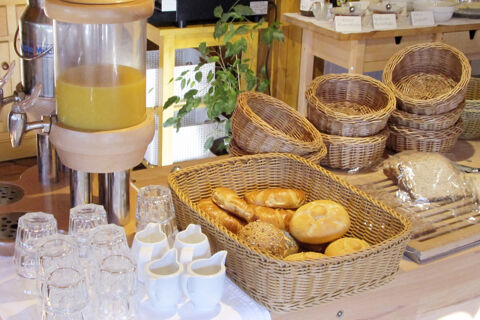 Fr&uuml;hst&uuml;cksbereich mit verschiedenen Br&ouml;tchen, frisch gepresstem Saft, Gl&auml;sern und Marmeladen im Bauernhof W&auml;ldebauernhof Buffet