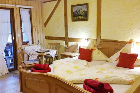 Gem&uuml;tliches Zimmer mit rustikalem Holzmobiliar, gepolsterten St&uuml;hlen und einem kleinen Tisch im Bauernhof W&auml;ldebauernhof.