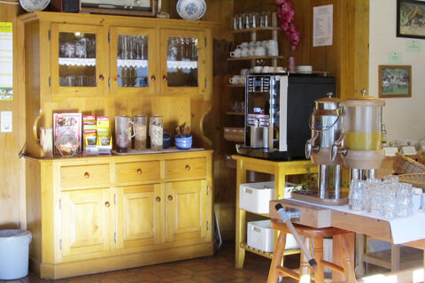 Fr&uuml;hst&uuml;cksecke mit Holzschrank, Cerealien, Kaffeeautomat und Saftspender im Bauernhof W&auml;ldebauernhof f&uuml;r G&auml;ste.