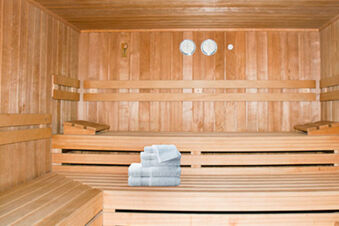 Innenansicht einer Holzsauna mit Saunab&auml;nken und wei&szlig;en Handt&uuml;chern im Hotel Landgut Burg f&uuml;r entspannende Wellnessmomente.